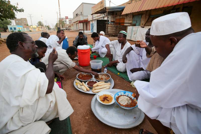 Sudanese men break their fast in a street in the capital Khartoum during the Muslim holy month of Ramadan amid a curfew due to the COVID-19 coronavirus pandemic.  AFP