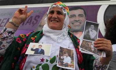 A supporter of Turkey's main pro-Kurdish Peoples' Democratic Party (HDP) holds pictures of their jailed former leader and presidential candidate Selahattin Demirtas during a campaign event in Istanbul, Turkey May 25, 2018. REUTERS/Huseyin Aldemir       NO RESALES. NO ARCHIVES.
