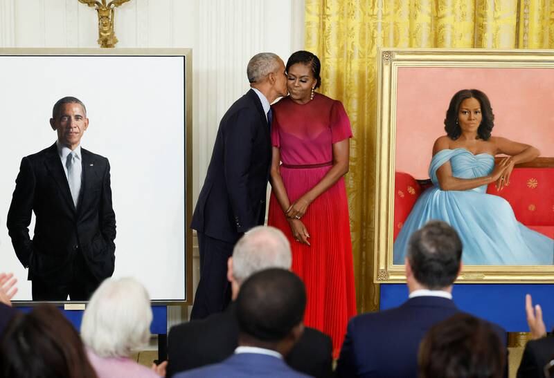 Former US president Barack Obama kisses former first lady Michelle Obama during the unveiling of their official White House portraits, painted by Robert McCurdy and Sharon Sprung, respectively. Reuters