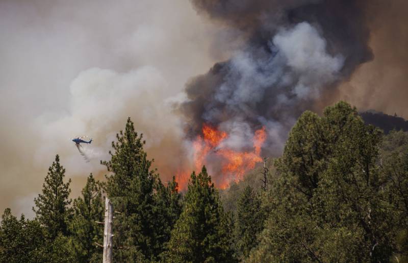 A helicopter drops water on the Oak Fire as it burns in Mariposa County, California. AP