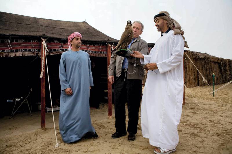 Abu Dhabi Crown Prince Sheikh Mohammed Bin Zayed al-Nahayan (R) looks on as US President George W. Bush holds a falcon at the the Royal Stables of the Al-Asayel Racing and Equestrian Club in Suwaihan, some 30 Kms outside Abu Dhabi, 13 January 2008 ahead of a dinner. Bush reached out to the Iranian people today in the keynote address of a Middle East tour, telling them they had a right to live under a government "that listens to your wishes". Person on the left is unidentified. AFP PHOTO/MANDEL NGAN (Photo by MANDEL NGAN / AFP)
