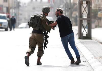 Israeli soldier holds back a settler during confrontations at the scene of a shooting attack in the West Bank town of Hawara. EPA