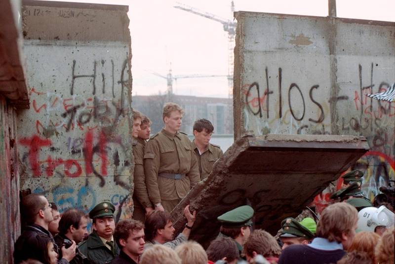 East German border guards are seen through a gap in the Berlin wall after demonstrators pulled down a segment of the wall at Brandenburg gate, Berlin. AP Photo