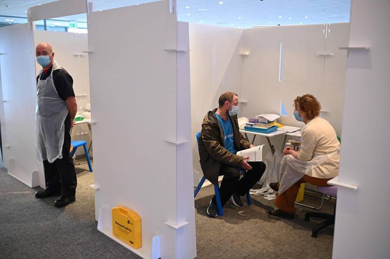 A vaccinator talks with a patient in a booth at the vaccination centre set up at Chester Racecourse. AFP