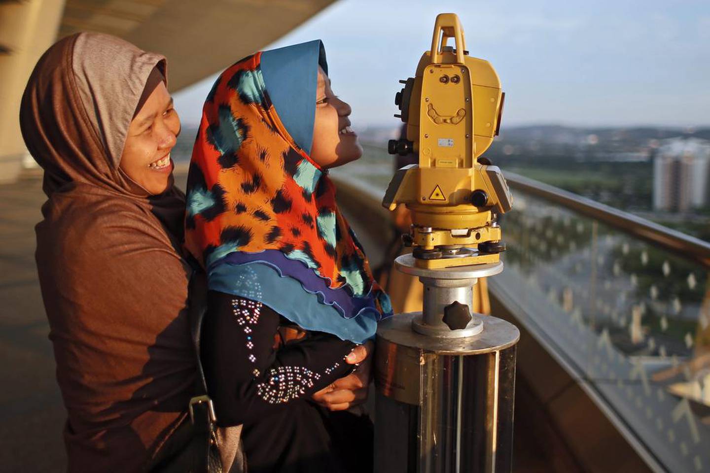 A mother and daughter look through a telescope to determine the sighting of the new moon to mark the start of the fasting month of Ramadan in Putrajaya, outside Kuala Lumpur, Malaysia, on June 15, 2021. EPA