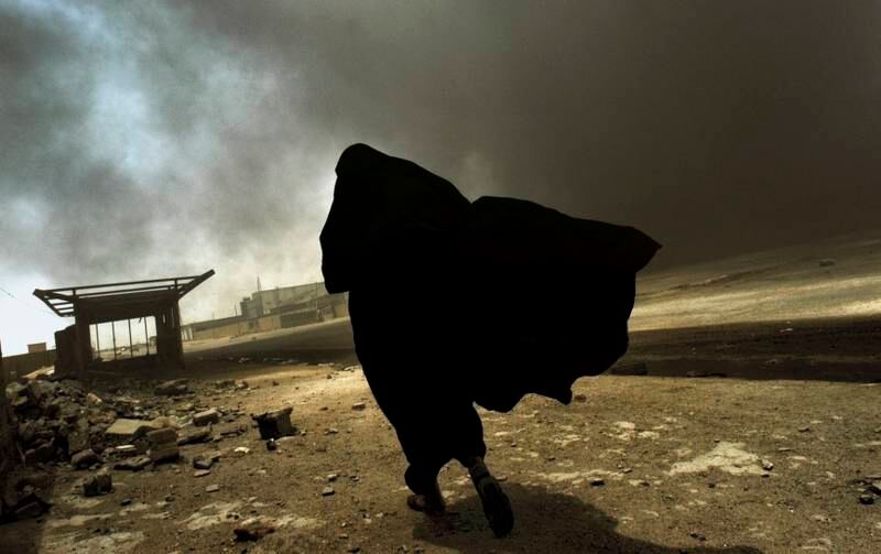A woman walks through smoke rising from a massive fire at a liquid gas factory, as she searches for her husband, in Basra, southern Iraq, in May 2003. All photos: Lynsey Addario