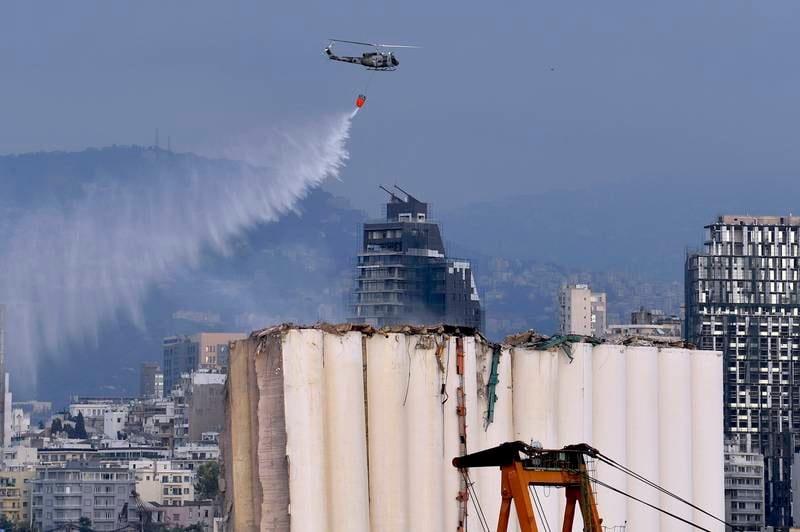 An army helicopter drops water on the silos. Part of the northern block, already heavily damaged in the 2020 blast and the recent fire, collapsed in a huge cloud of dust on Sunday. EPA
