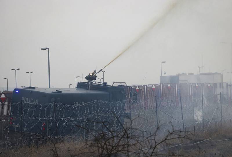 Polish servicemen use a water cannon at the border.  Polish border forces said they were attacked with stones by migrants. AP