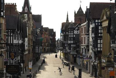 A man plays with a football on Eastgate Street in a near-deserted Chester city centre in north-West England as the warm weather tests the nationwide lockdown to combat the novel coronavirus pandemic.  AFP