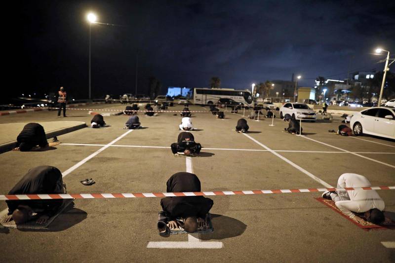 Palestinian and Arab Israeli men keep a 2 metre distance amid the Covid-19 pandemic, as they pray in a parking lot near the beach in Jaffa, near the Israeli coastal city of Tel Aviv, after breaking their fast, on the second day of Ramadan.  AFP