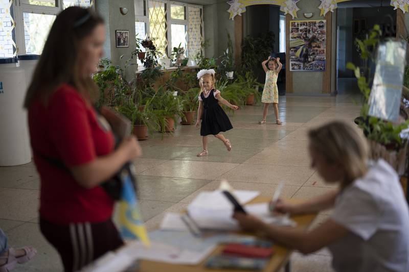 Girls play as a woman distributes iodine tablets to residents at a local school in case of a radiation leak in Zaporizhzhia. AP
