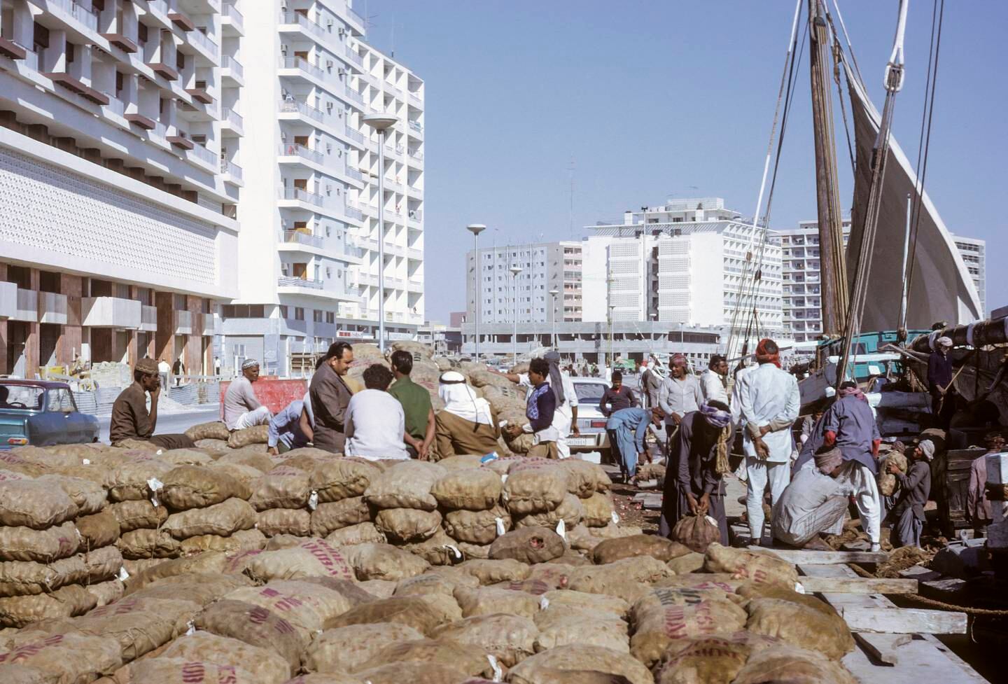 Cargo being unloaded from a dhow in Dubai Creek in 1972 with office and apartment buildings in the background. ©Charles O. Cecil / Cecil Images