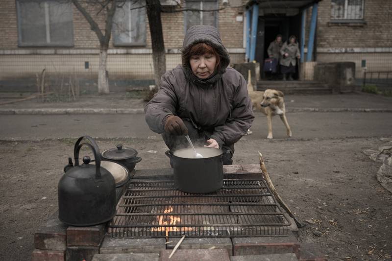 A woman cooks on an open fire outside an apartment building, in Bucha. AP
