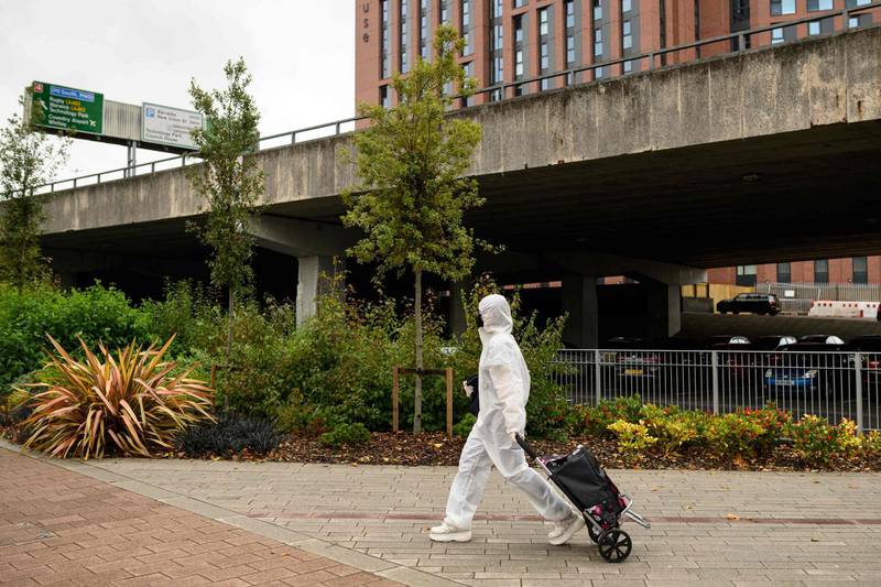 A student wearing full-body PPE walks towards the Coventry University Library . AFP