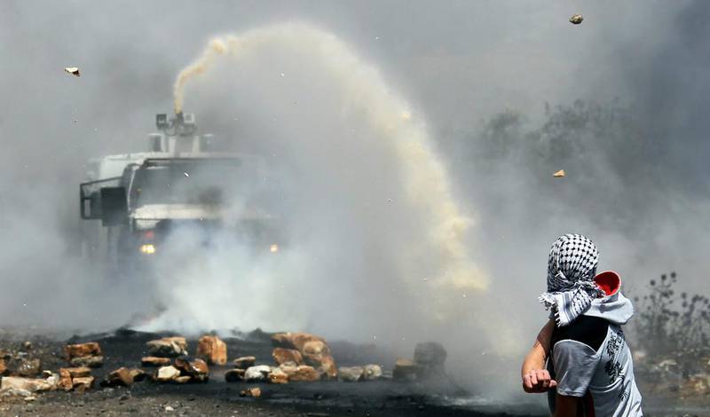 Palestinian protester hurls stones at Israeli army water canon during weekly clashes over the Jewish settlement of Qadomem at Kofr Qadom village, near West Bank city of Nablus. Twelve Palestinians were reportedly wounded during the clashes accompanying the weekly Friday demonstrations of Palestinians against Jewish settlements. Alaa Badarneh / EPA
