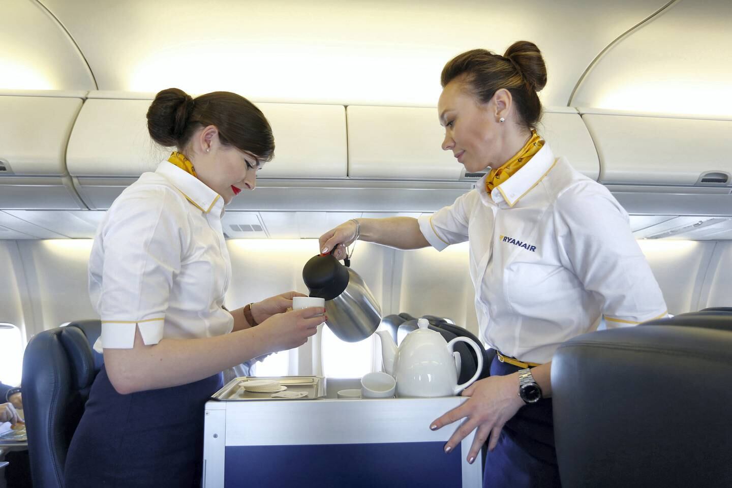 Air stewardesses serve coffee in the cabin of the Ryanair Holdings Plc corporate jet during a flight to Dublin, Ireland, on Tuesday, April 12, 2016. Ryanair attracted more than 100 million travelers for the first time in 2015 and is set to overtake EasyJet Plc as the biggest airline operating in the U.K., with a total of 41 million passengers forecast this year, chief executive officer Michael O'Leary said. Photographer: Luke MacGregor/Bloomberg