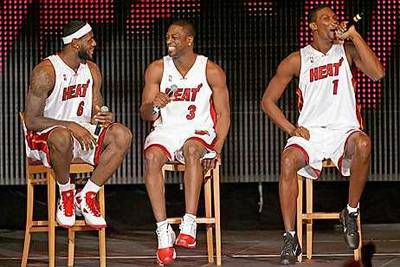 LeBron James, left, and Dwyane Wade listen as new teammate Chris Bosh speaks to fans.