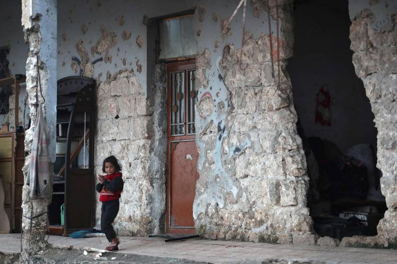 A child stands outside an abandoned school building in Idlib province. Families, mostly displaced from the Maaret Al Noman area, south of Idlib city, have taken shelter in the school. AFP