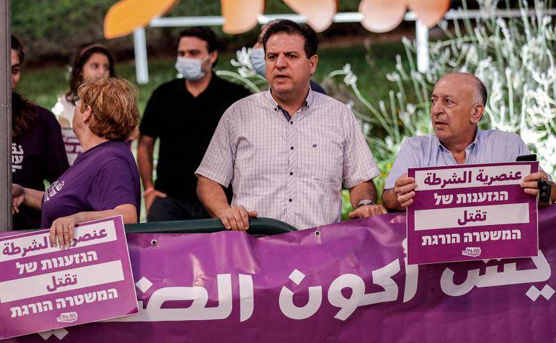 Ayman Odeh (C), leader of Israel's predominantly Arab Joint List electoral alliance and its constituent Hadash Party, stands between two people holding signs reading in Arabic and Hebrew "police racism kills" during a protest against the government's insufficient handling of rising violence levels within the Arab community, outside the home of Public Security Minister Omer Bar-Lev in the northern Israeli town of Kokhav Yair. AFP