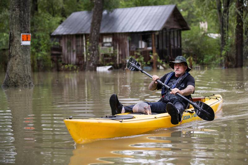 Donnie McCulley paddles out from a flooded neighborhood caused by heavy rain spawned by Tropical Depression Imelda with an armadillo as a passenger. AP
