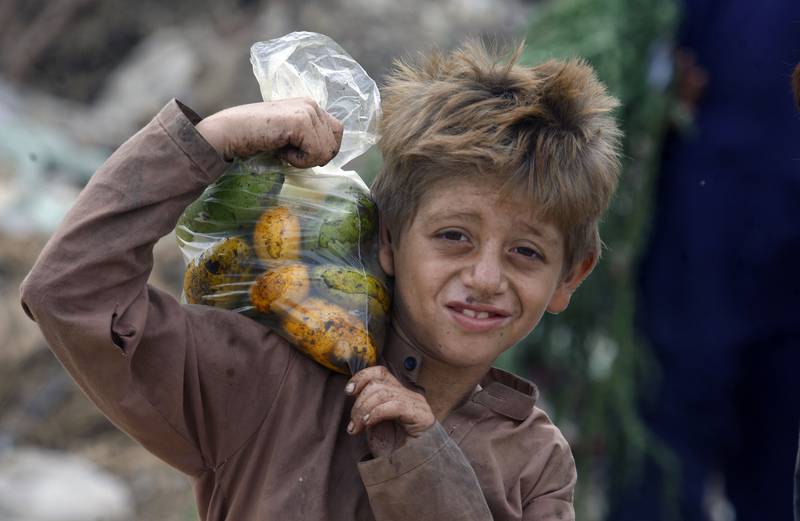 An Afghan refugee boy carries a bag of mangoes on his shoulder in Karachi, Pakistan. AP