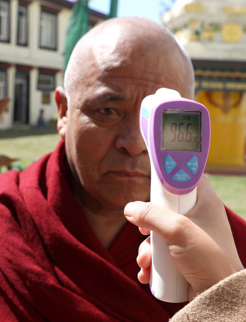 A doctor checks the temperature of a Tibetan man, living-in-exile in India, outside the Tibetan Parliament house during the Parliament session at Dharamsala, India.  EPA