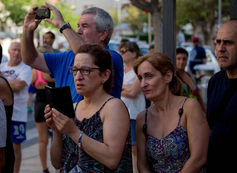 People watch the spot where terrorists were intercepted by police in Cambrils, Spain, Friday, Aug. 18, 2017. Spanish police on Friday shot and killed five people carrying bomb belts who were connected to the Barcelona van attack that killed at least 13, as the manhunt intensified for the perpetrators of Europe's latest rampage claimed by the Islamic State group. (AP Photo/Emilio Morenatti)