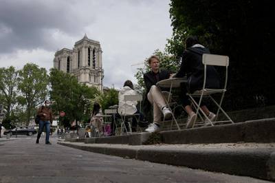 People sit outdoors at a restaurant terrace near Notre Dame cathedral in Paris, France. Cafe and restaurant terraces reopened this week after a pandemic shutdown of more than six months. AP Photo
