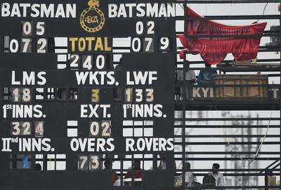 Scorers peer out from the empty spaces of the manual scoreboard during a practice cricket match between New Zealand and Mumbai at the Ferozshah Kotla ground in New Delhi. Prakash Singh / AFP