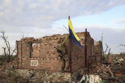 An assault unit commander raises the Ukrainian flag as a symbol of liberation of the frontline village of Andriivka. AP