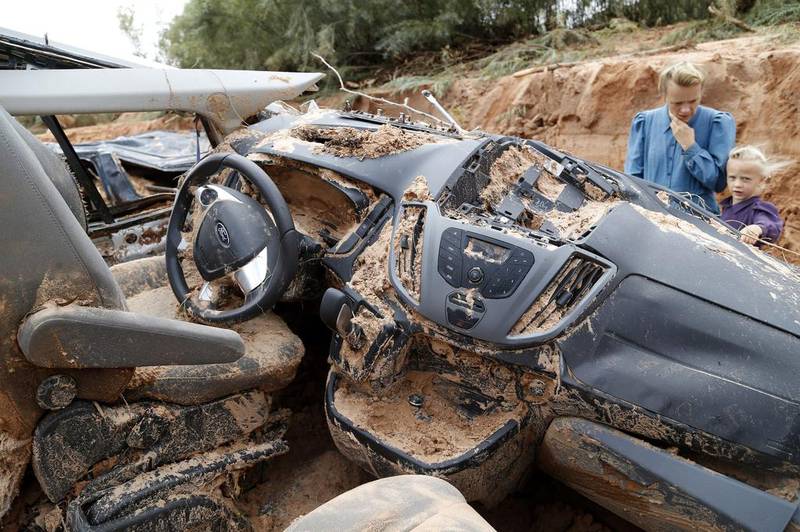 A woman and child examine a vehicle swept away during a flash flood in Hilldale, Utah. Authorities say several people have died in flash flooding that swept away vehicles in a polygamous community on the Utah-Arizona border. Michael Chow / The Arizona Republic via AP