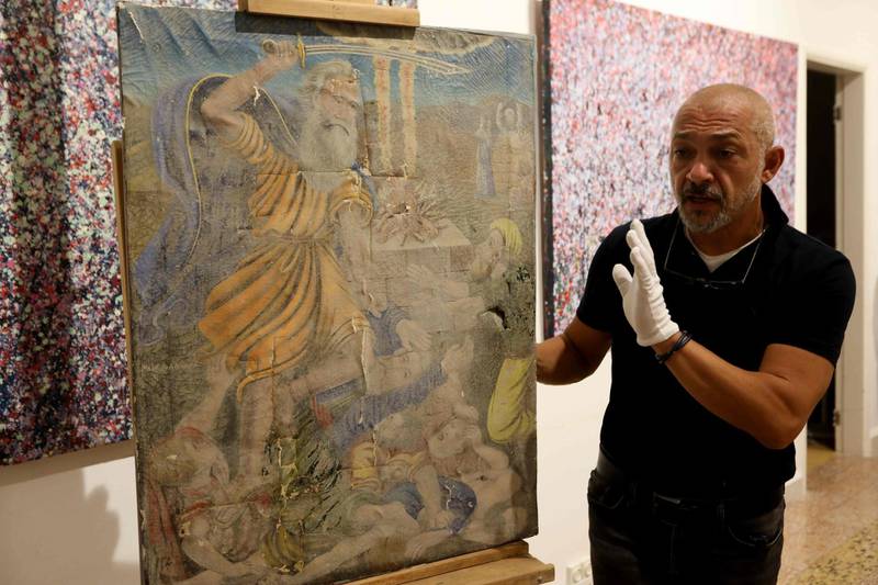 Gaby Maamary, a Lebanese artwork conservation specialist, examines a 19th-century painting, damaged in the Beirut port blast.