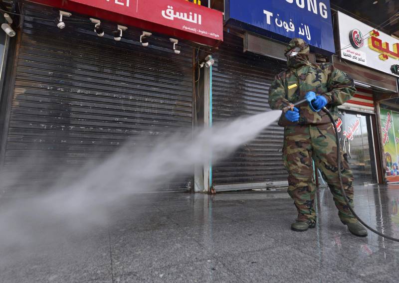 A member of the Iraqi civil defense sprays disinfectant on and around a building where Islamic students are quarantined for having had contact with Iraq's first confirmed case of novel coronavirus infection, in the central holy city of Najaf, on February 26, 2020. Najaf's authorities have beefed up precautionary measures since Iraq's first case of COVID-19 infection was confirmed on February 24, in an Iranian national studying in a Shiite seminary in the holy city. / AFP / Haidar HAMDANI
