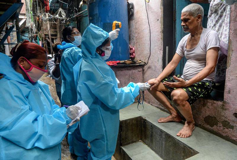 Health workers wearing Personal Protective Equipment use a fingertip pulse oximeter and check the health of a resident inside the Dharavi slum during door-to-door coronavirus screening in Mumbai.  AFP