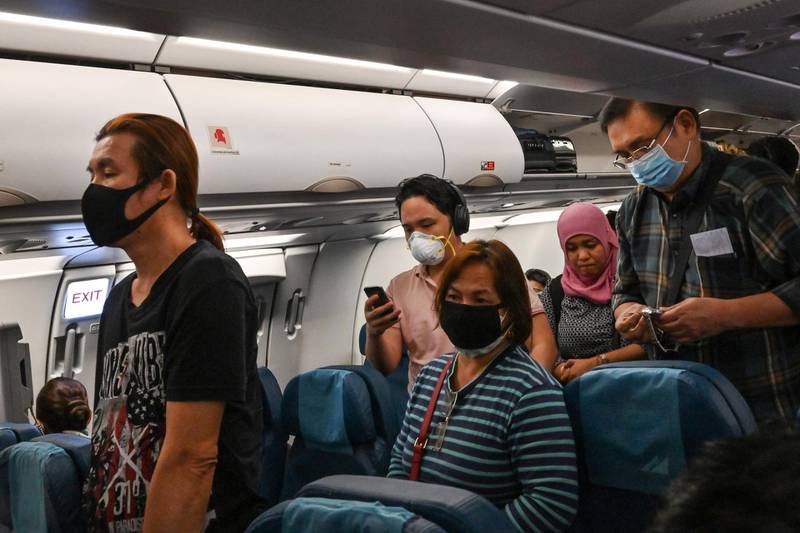 This photo taken on February 23, 2020 shows passengers wearing protective facemasks, amid concerns of the spread of the COVID-19 novel coronavirus, prepare to disembark from a flight originating from Manila upon their arrival at Suvarnabhumi Airport in Bangkok.   / AFP / Romeo GACAD

