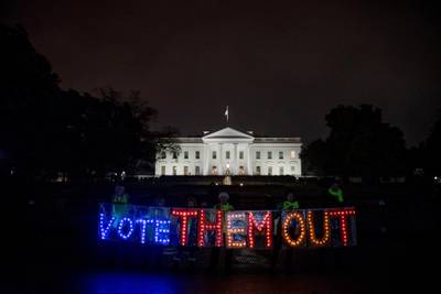 A group of people hold up a sign that reads "Vote Them Out" as they protest in front of the White House the night before midterm election voting begins in Washington. AP