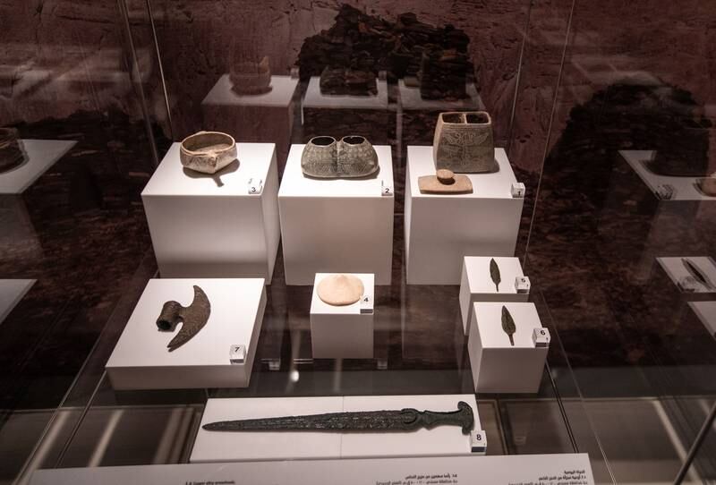 A collection of soft-stone compartmented vessels, a copper alloy axe, a shell medallion, copper alloy arrowheads and a dagger from the Iron Age
