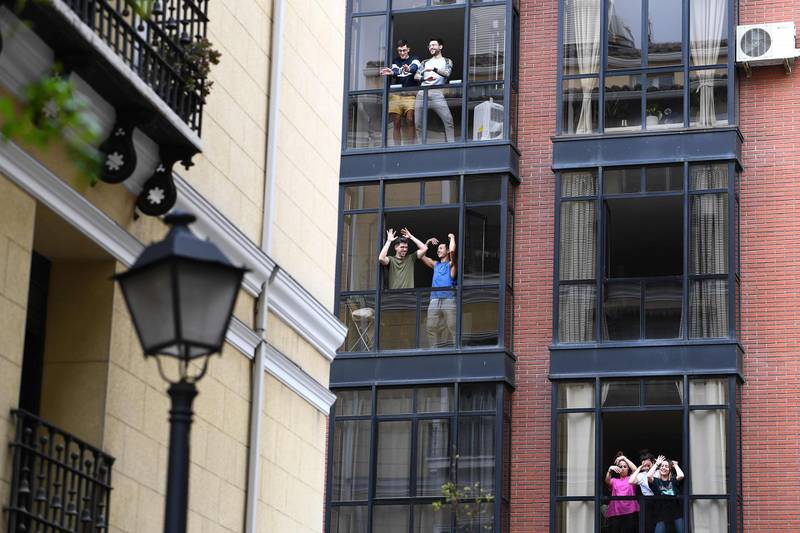 People confined at their homes sing and dance from their windows to bolster themselves up during a lockdown in Madrid. AFP