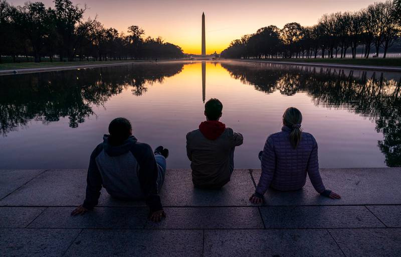 A trio of friends watch the sunrise at the Reflecting Pool near the Lincoln Memorial in Washington, two days after Election Day. AP Photo