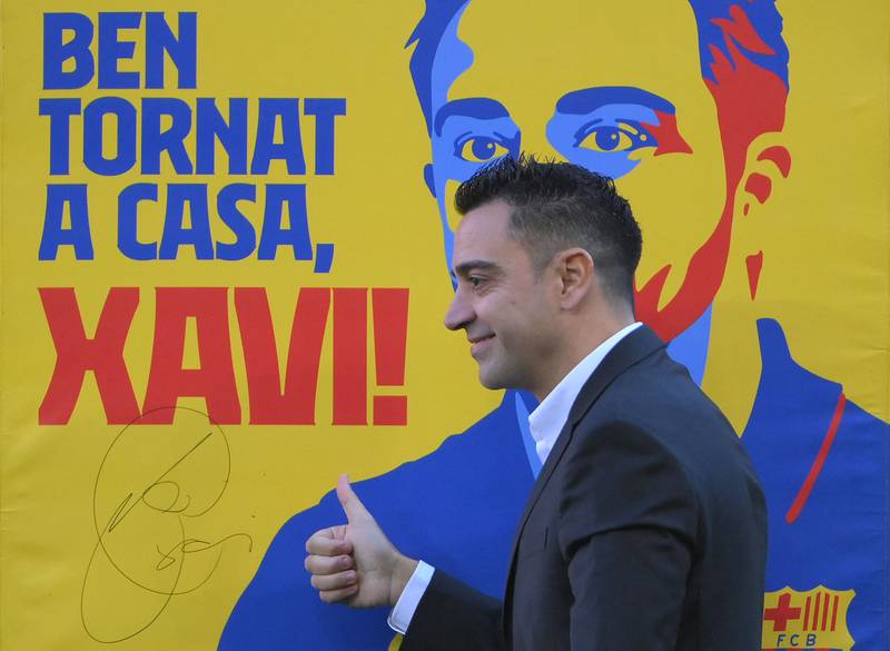 Xavi Hernandez poses next to a poster reading "welcome back", during his presentation ceremony at Camp Nou. AFP