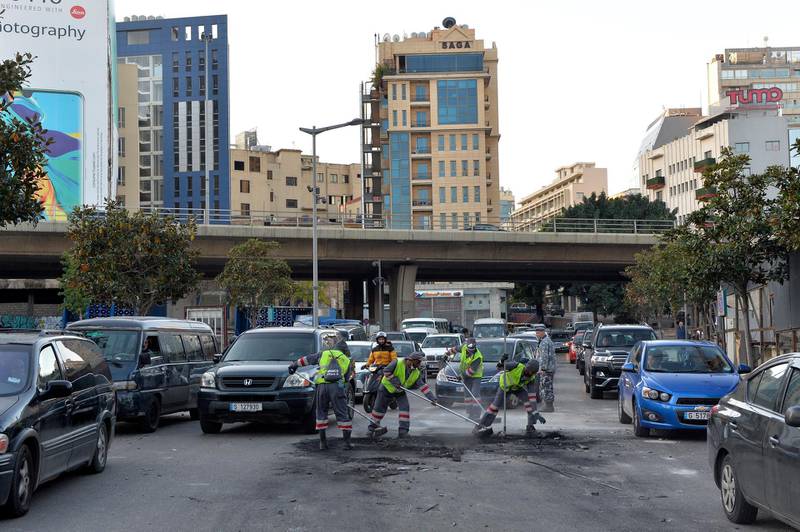 People clean up a street after a night of clashes between supporters of Hezbollah and Amal and security forces. EPA