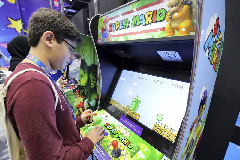 Dubai, United Arab Emirates - April 11, 2019: Visitors play on old arcade games at the Middle East Film and Comic Con. Thursday the 11th of April 2019. World Trade Centre, Dubai. Chris Whiteoak / The National