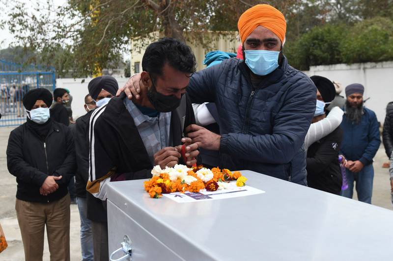 Sukhdev Singh (L) brother of Hardev Singh, who was killed on the January 17 drone attack in Abu Dhabi, mourns over his brother's coffin at the Sri Guru Ram Dass Jee International Airport on the outskirts of Amritsar on January 21, 2022. AFP