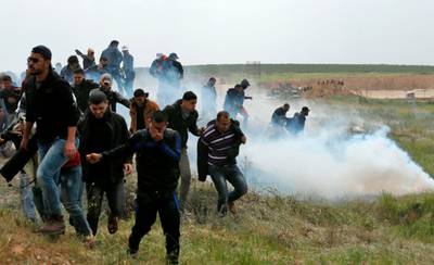 Palestinian protesters run from tear-gas during clashes near the border with Israel east of Gaza City on March 30, 2018. Mahmud Hams / AFP