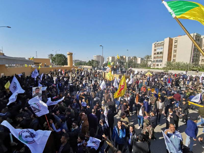 Protesters and militia fighters gather outside the main gate of the US embassy in Baghdad. Reuters