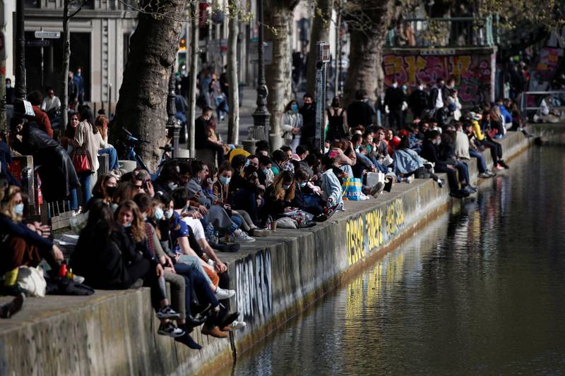 People sit along the Canal Saint-Martin in Paris, France, as the country enters its third lockdown. Reuters