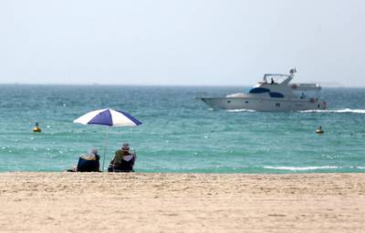 Dubai, United Arab Emirates - Reporter: N/A. News/Weather. A couple watch a yacht go passed from the beach on a hot day in Dubai. Sunday, June 14th, 2020. Dubai. Chris Whiteoak / The National