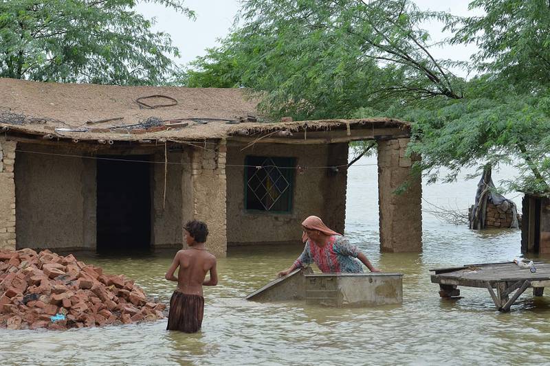 A woman moves metal trunks in front of her home in knee-deep flood waters in Jaffarabad district in Balochistan province.  EPA