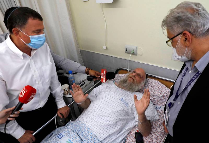 An injured man talks to reporters as Israeli Health Minister Yuli Edelstein, left, visits the wounded at Ziv hospital, in the northern city of Safad. AFP
