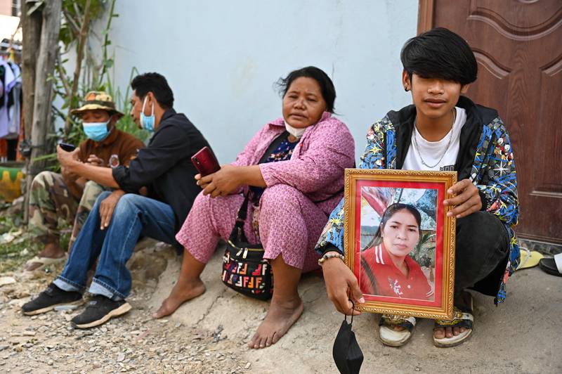 A youth holds a framed portrait of his mother who is missing following the fire. AFP